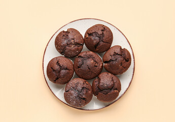 Plate with tasty chocolate cupcakes on beige background