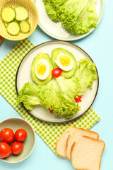 Plate with funny breakfast in shape of owl, vegetables and bread on blue background