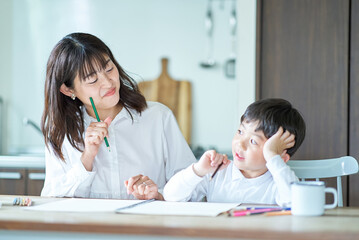 部屋で鉛筆とノートを使って勉強する親子