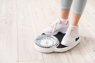 Young woman measuring her weight on scales at home, closeup