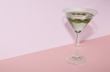 Glass of martini with olives on color background