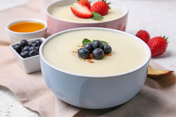 Bowls of tasty semolina porridge with strawberry and blueberry on table