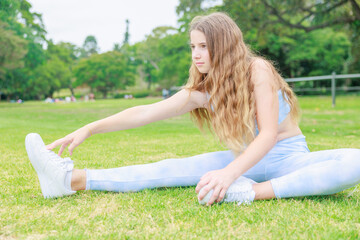Naklejka na ściany i meble 公園の芝生に座りストレッチをするオーストラリアの中学生