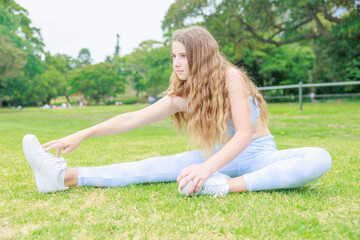Naklejka na ściany i meble 公園の芝生に座りストレッチをするオーストラリアの中学生