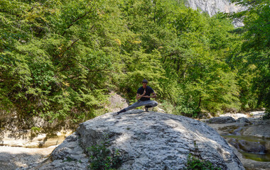 Nin-Dzutsu. This man meditates on a big rock. There is a green forest on the background.