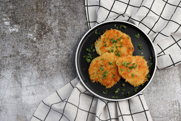 Rustic hash browns with chives on a round plate on a dark background. Top view, flat lay