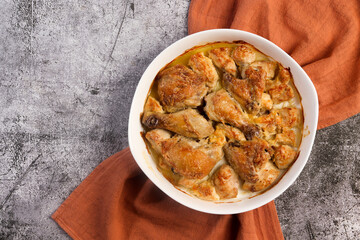 Classic Baked Chicken Pieces in a white baking dish on a dark grey background. Top view, flat lay