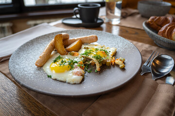 closeup shot of sausage, potato, scrambled eggs, on a grey plate. Traditional European English breakfast.