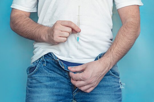 protection of sexually transmitted infections. a man holds a syringe in his hands and takes off his jeans. The concept of treatment of sexually transmitted diseases.