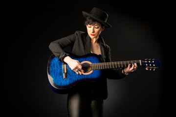 A young, beautiful woman in black with an acoustic blue guitar