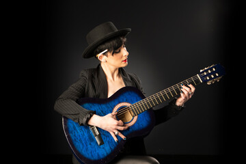 A young, beautiful woman in black with an acoustic blue guitar