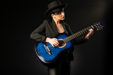 A young, beautiful woman in black with an acoustic blue guitar