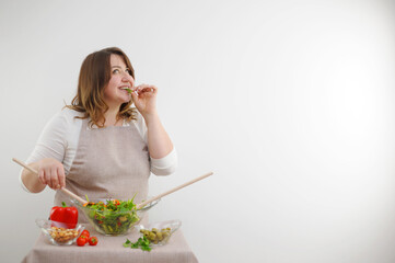 Smiling young woman eating fresh salad in modern kitchen Close-up of pretty girl eating fresh vegetable salad. High quality photo