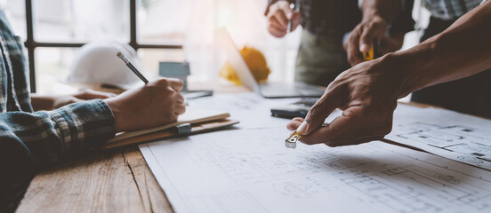 A group of engineers and architects are brainstorming, analyzing and taking notes using tape...