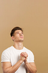 Handsome man looking up while praying with folded hands