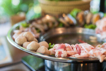 closeup jaew hon or isan hot pot and sukiyaki shabu with raw pork meat ball and seafood with boiling spicy thick soup in silver ware pot for lunch or dinner and thai street food boiled at restaurant