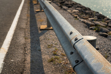 Roadside metal rail barrier structure which is installed on side of the road for protected the car accident. Transportation safety equipment object, selective focus.