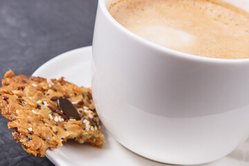 Cup of coffee with milk and fresh baked oatmeal cookies with honey and healthy seeds. Delicious crunchy dessert