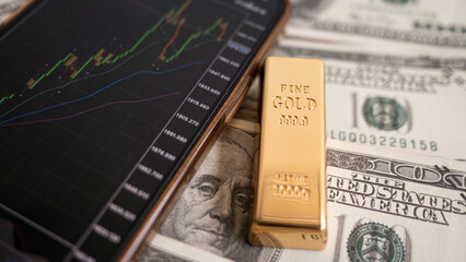 gold bars place on the phone that opens the candlestick chart. and dollar. Fluctuations in gold prices concept.