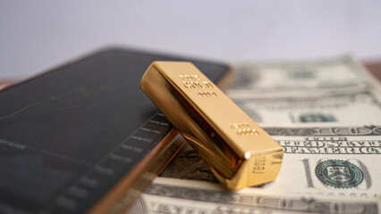 gold bars place on the phone that opens the candlestick chart. and dollar. Fluctuations in gold prices concept.