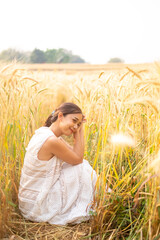Young Asian women  in white dresses sitting in the Barley rice field season golden color of the wheat plant at Chiang Mai Thailand