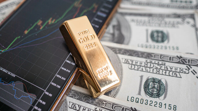 gold bars place on the phone that opens the candlestick chart. and dollar. Fluctuations in gold prices concept.