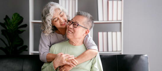 Senior woman embracing with beloved while sitting on the couch a