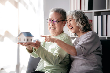 Senior couple holding house model for buying in life retirement