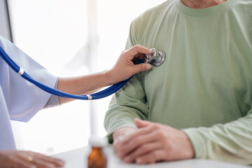 Female doctor using stethoscope to listening heart rate of senio