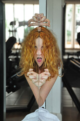 Portrait and hands of scary redhead woman with tongue out, creepy face in mirror, female duality,...