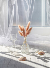 Still life with spikelets in a vase on a white windowsill on a sunny day