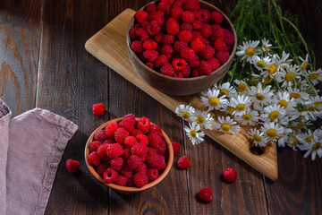 Fresh raspberries in a clay and wooden bowl on a dark wooden table