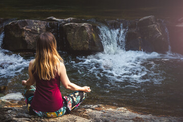 Woman doing yoga on the stone at the mountain river. Carpathians