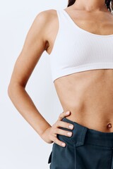 A woman with a beautiful body and tanned skin poses in white on a white background in her studio wearing home clothes and smiling beautifully with her teeth