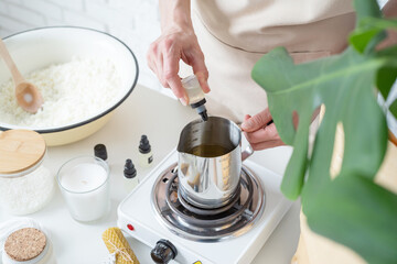 Woman making decorative aroma candle adding aroma, closeup