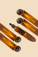 Bright pattern of mock up of glass vials with dropper lid in sunlight on beige background. Unmarked...