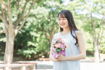 Fototapeta premium 花束・ブーケを持つ笑顔のアジア人女性（記念日・ギフト） 