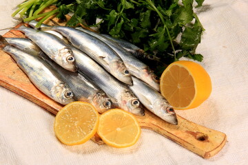 Fresh sardines with lemon and parsley on a wooden board. Fresh Baltic herring