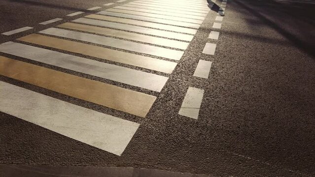 a girl walks along a pedestrian crossing in the rays of sunset