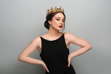 Beautiful young woman wearing luxurious crown on light grey background © New Africa