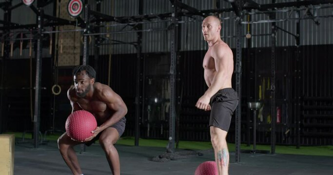 young strong diverse multiethnic group of young people doing medicine ball exercise. instructor teaches black man to throw ball over the head, shoulder slow motion