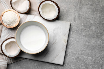 Bowl of delicious coconut milk, flakes and coconuts on light grey table, flat lay. Space for text
