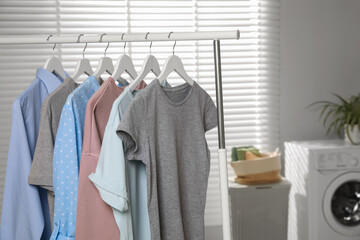 Different apparel hanging on clothes rack in bathroom, space for text