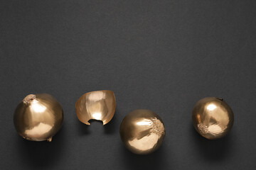 Golden onions on black background, flat lay. Space for text
