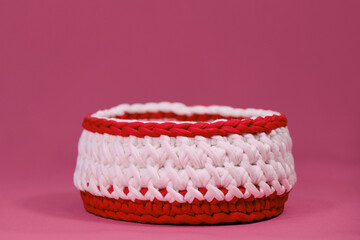 Crochet Home Basket on pink background. Red and white round box for small things made of thread...
