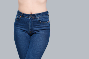 Woman in stylish jeans on grey background, closeup. Space for text