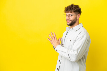 Young handsome caucasian man isolated on yellow background scheming something