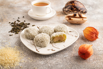 Japanese rice sweet buns mochi filled with pandan jam on brown concrete, side view.