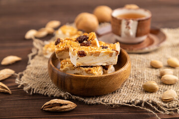 Traditional candy nougat with nuts and sesame on brown wooden, side view, selective focus.