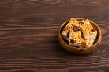 Traditional candy nougat with nuts and sesame on brown wooden, side view, copy space.